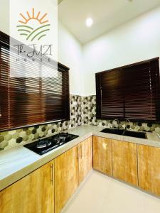 a kitchen with wooden cabinets and a sink at The Juzi House - private pool homestay in Kuala Terengganu