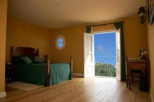 a bedroom with a bed and an open door at Colina Da Faja in Fajã da Ovelha