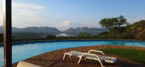 a swimming pool with two white chairs next to it at Katima Mountain View Lodge in Hartbeespoort