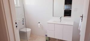 a white bathroom with a toilet and a sink at Inviting Stay Close to Rockingham and Palm Beach - Hosted by Canstay in Rockingham