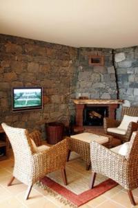 a living room with chairs and a stone fireplace at Colina Da Faja in Fajã da Ovelha