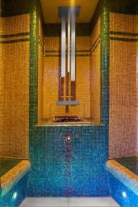 a bathroom with a tub with blue tiles at Retro Riverside Wellness Resort in Karlovy Vary