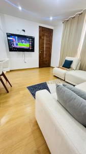 a living room with a couch and a flat screen tv at El Oasis de Huacachina - Alojamiento in Ica