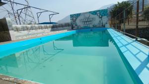 a swimming pool with blue water at Thakur Farm in Palasdhari
