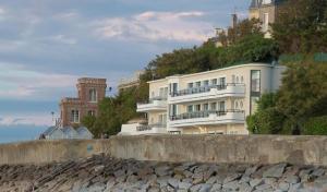 a large white building on a hill next to the ocean at Le Paquebot in Villerville +18 photos