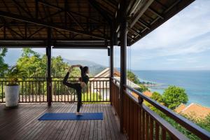 una mujer haciendo yoga en el balcón de una casa en Napasai Samui, en Mae Nam
