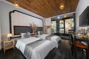 ein Zimmer mit drei Betten und einem Schreibtisch und einem Fernseher in der Unterkunft Trang An Ecorest Resort & Spa in Xuân Sơn