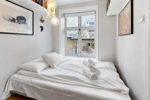 Una cama blanca en una habitación con ventana. en Dinbnb Homes I Family Friendly Home in Historical Sandviken, en Bergen