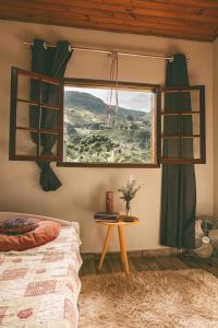 1 dormitorio con 1 cama y ventana con mesa en Casinha Pedra do Baú, en São Bento do Sapucaí