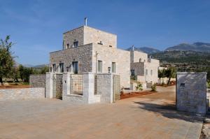 a large stone building with mountains in the background at Nikoloudi Estate in Agios Nikolaos