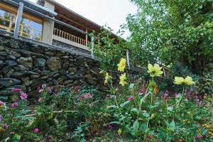a garden with flowers and a stone wall at Ulugbeks guesthouse in Yukary-Ukhum