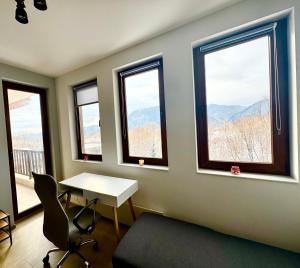 a room with a table and windows with a view at Хубавото място - Ski & Relax next to Pamporovo in Smolyan
