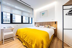 a bedroom with a yellow bed and a desk at Apartamentos París Boutique Valladolid in Valladolid