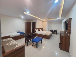 a room with two beds and a tv and chairs at K P M Lodge in Atmakūr