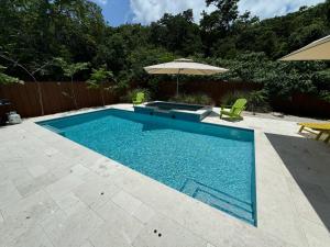 a swimming pool with an umbrella and two chairs and a table at Key Largo Home with Spa and Pool in Key Largo