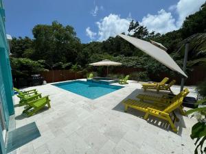 a swimming pool with yellow chairs and an umbrella at Key Largo Home with Spa and Pool in Key Largo