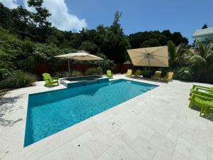 a swimming pool with chairs and an umbrella at Key Largo Home with Spa and Pool in Key Largo