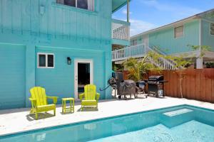 una casa blu con sedie gialle e una piscina di Key Largo Home with Spa and Pool a Key Largo