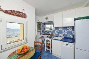 a kitchen with a table with a bowl of fruit on it at Beach House Ischia - Seafront & Aragonese Castle View - in Ischia Town +29 photos