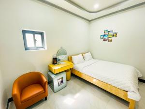 a small bedroom with a bed and a chair at Sand Sea Hotel Phan Thiết in Phan Thiet