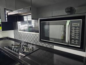 a kitchen with a stove and a microwave at Thea Homestay in Sepang