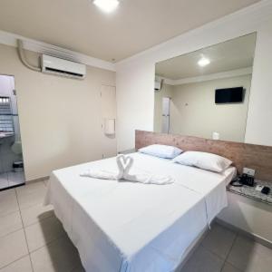 a large white bed in a room with a mirror at Basic Hotel Praia in Aracaju