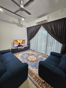 a living room with a blue couch and a tv at Thea Homestay in Sepang
