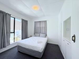a white bedroom with a bed and a window at Unit 11 Fenton Summer Lodge Rotorua in Rotorua