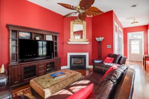 a living room with red walls and a couch and a television at Seaside Creole Cottage in Gulfport