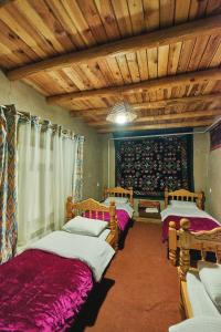 two beds in a room with wooden ceilings at Ulugbeks guesthouse in Yukary-Ukhum