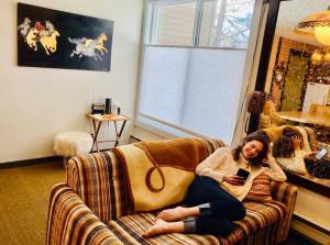 a woman sitting on a couch holding a cell phone at Innsbruck Walkable to Big Sky Resort in Big Sky