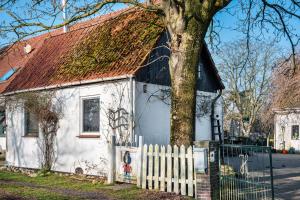 a small white house with a red roof and a tree at Harmonie Tiny House in Oyten