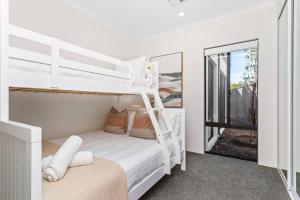 a white bedroom with a bunk bed and a mirror at Spacious and modern Dianella in Perth