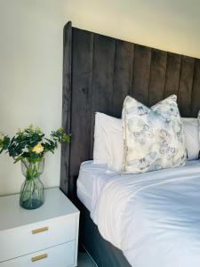 プレトリアにある1 bedroom- The Blyde by Givenのベッド(木製のヘッドボード、花瓶付)