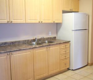 a kitchen with a sink and a refrigerator at Hotel Laurier - Apartment Style Residence in Waterloo