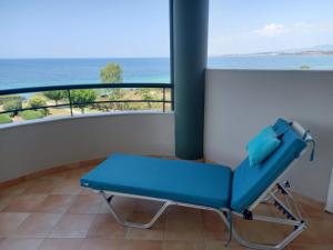 a blue chair on a balcony with a view of the ocean at Beach house in Nea Potidaea
