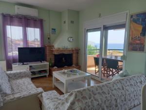 a living room with a couch and a television and a table at Beach house in Nea Potidaea