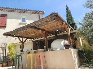 una cocina al aire libre con techo de madera en una casa en Chambre chez l'habitant avec piscine et cuisine d'été, en Saint-Martin-de-la-Brasque