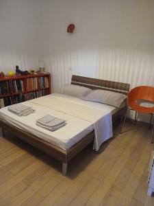 Una cama en una habitación con una silla y un estante para libros. en Chambre chez l'habitant avec piscine et cuisine d'été, en Saint-Martin-de-la-Brasque