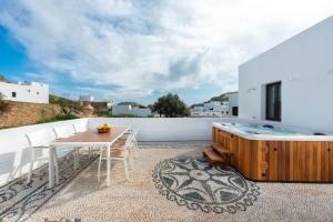 a patio with a wooden table and a hot tub at Lindos Diamond Exclusive Villa in Líndos