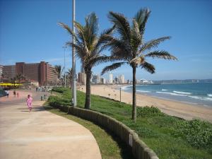 a child walking down a sidewalk next to a beach at Gooderson Leisure Silver Sands 2 Self Catering and Timeshare Lifestyle Resort in Durban