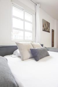 białe łóżko z 2 poduszkami i oknem w obiekcie RentalSevilla Guadalete I w Sewilli