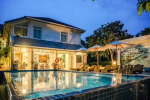 a swimming pool in front of a house with umbrellas at Villa Amphawa in Amphawa
