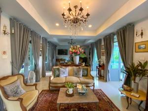 a living room with a couch and a chandelier at Villa Amphawa in Amphawa