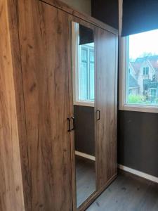 einen Holzschrank mit einem Spiegel in einem Zimmer mit 2 Fenstern in der Unterkunft attic apartment in the center in Gouda