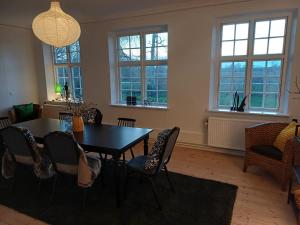 uma sala de jantar com mesa, cadeiras e janelas em Gartnerboligen Fuglsang em Toreby