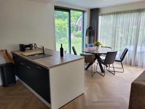 a kitchen with a sink and a table with chairs at De Bosanemoon with Sauna | 6 persons in Gasselte