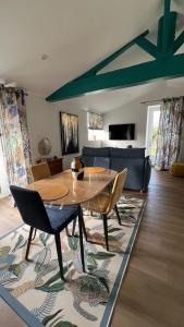 a living room with a wooden table and chairs at Gîtes de charme "l'écrin de Vendée" jacuzzi privatif, piscine chauffée, prestations bien être, vélos à 10 mn de l'océan sur 3,5 h de verdure in Sallertaine