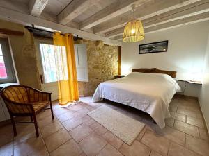 a bedroom with a white bed and a chair at Le Secret de St Cyprien in Saint-Cyprien