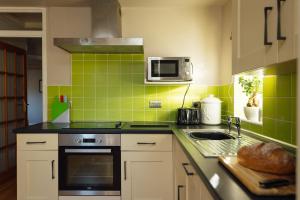 a kitchen with lime green tiles on the wall at Eira's Cottage in Nolton